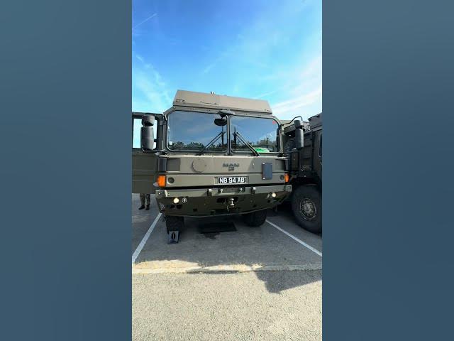Military truck parked, viewed from the front, under a clear blue sky.