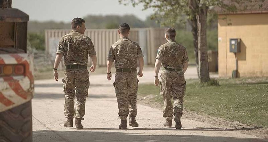 Three soldiers walking away from the camera down a road