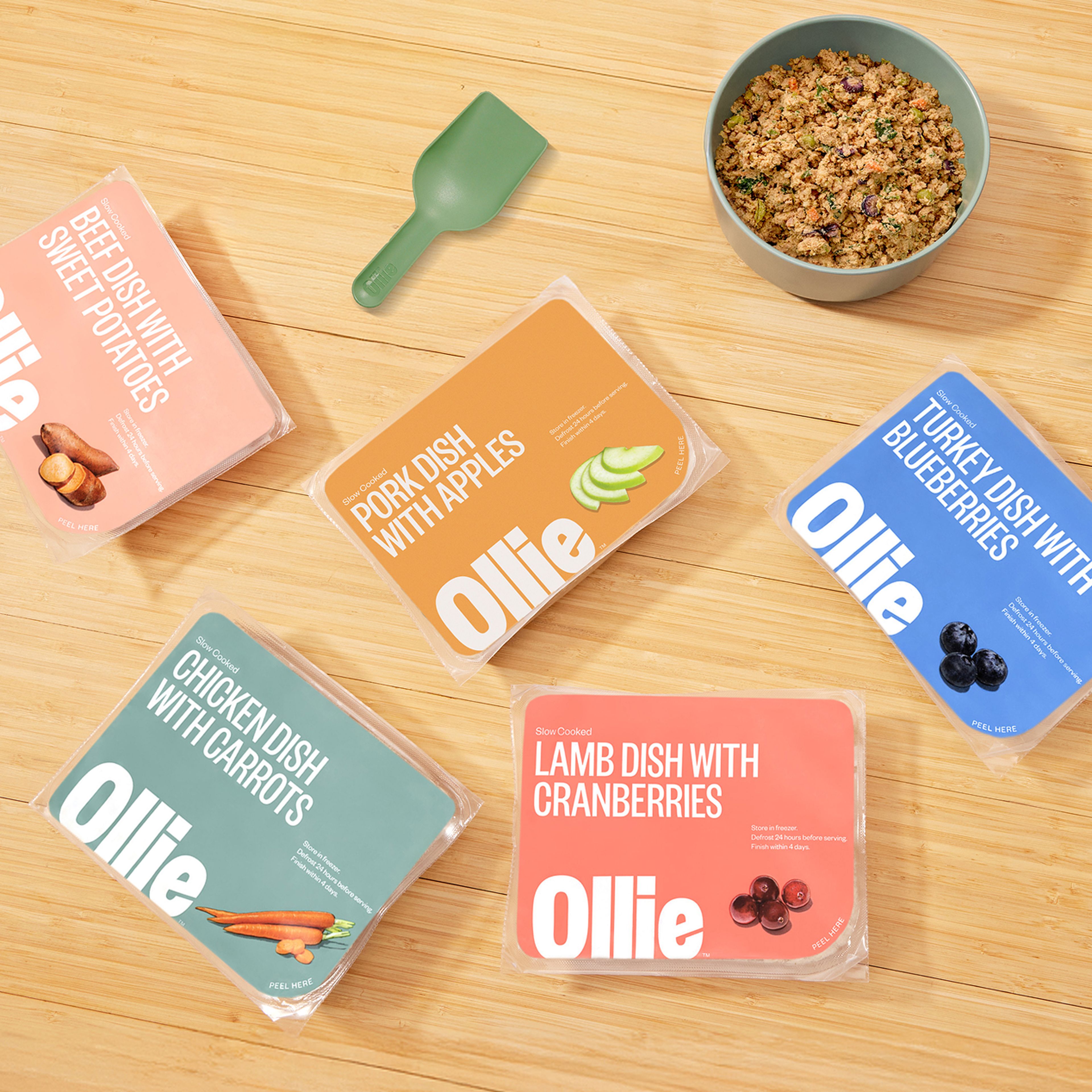 Images o our 5 fresh recipe packs of food on a table top next to our scoop and a fresh bowl of food