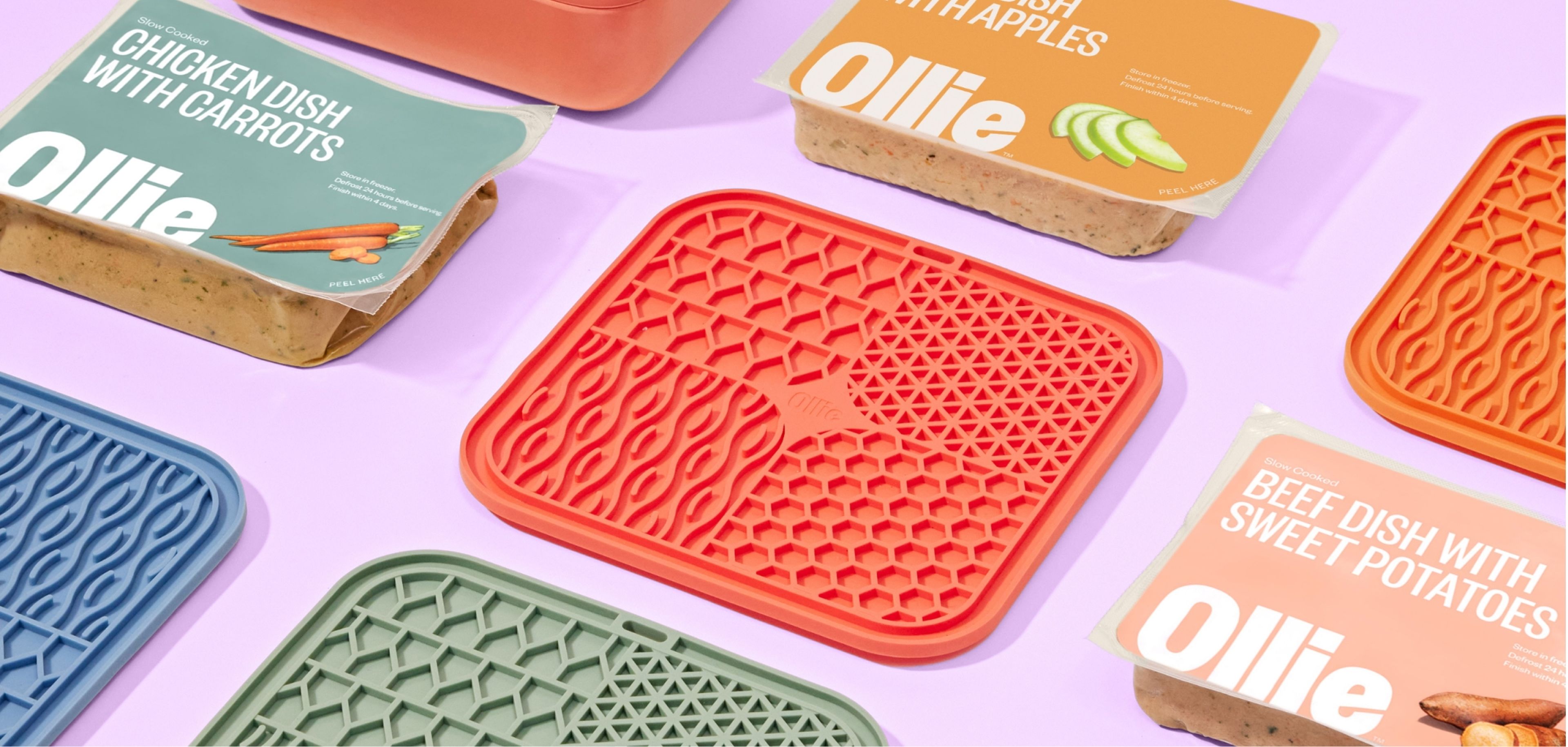 Colorful pet food packaging by Ollie, featuring chicken, apple, and beef dishes with textured mats beneath on a pastel background.