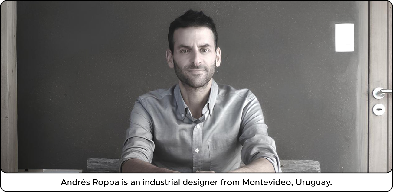 A man sitting at a table against a dark wall, wearing a light shirt, with a neutral expression.