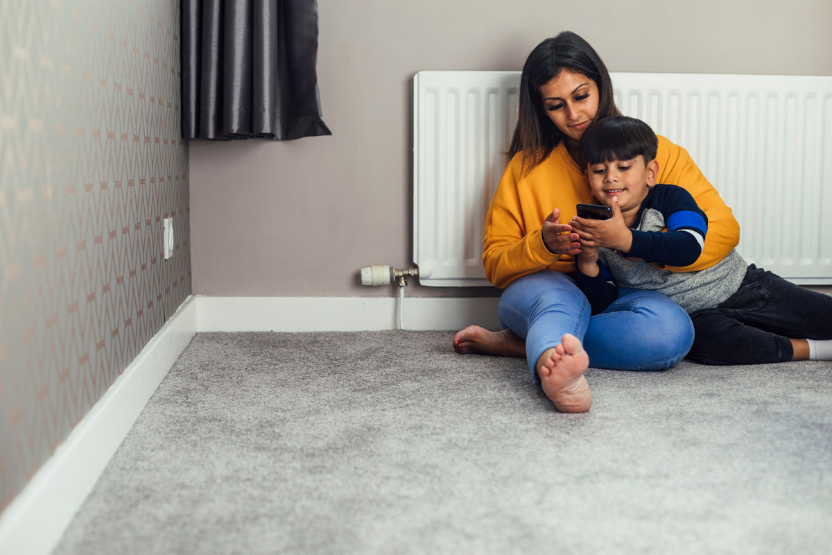Mother and son looking at a phone, sat by the radiator