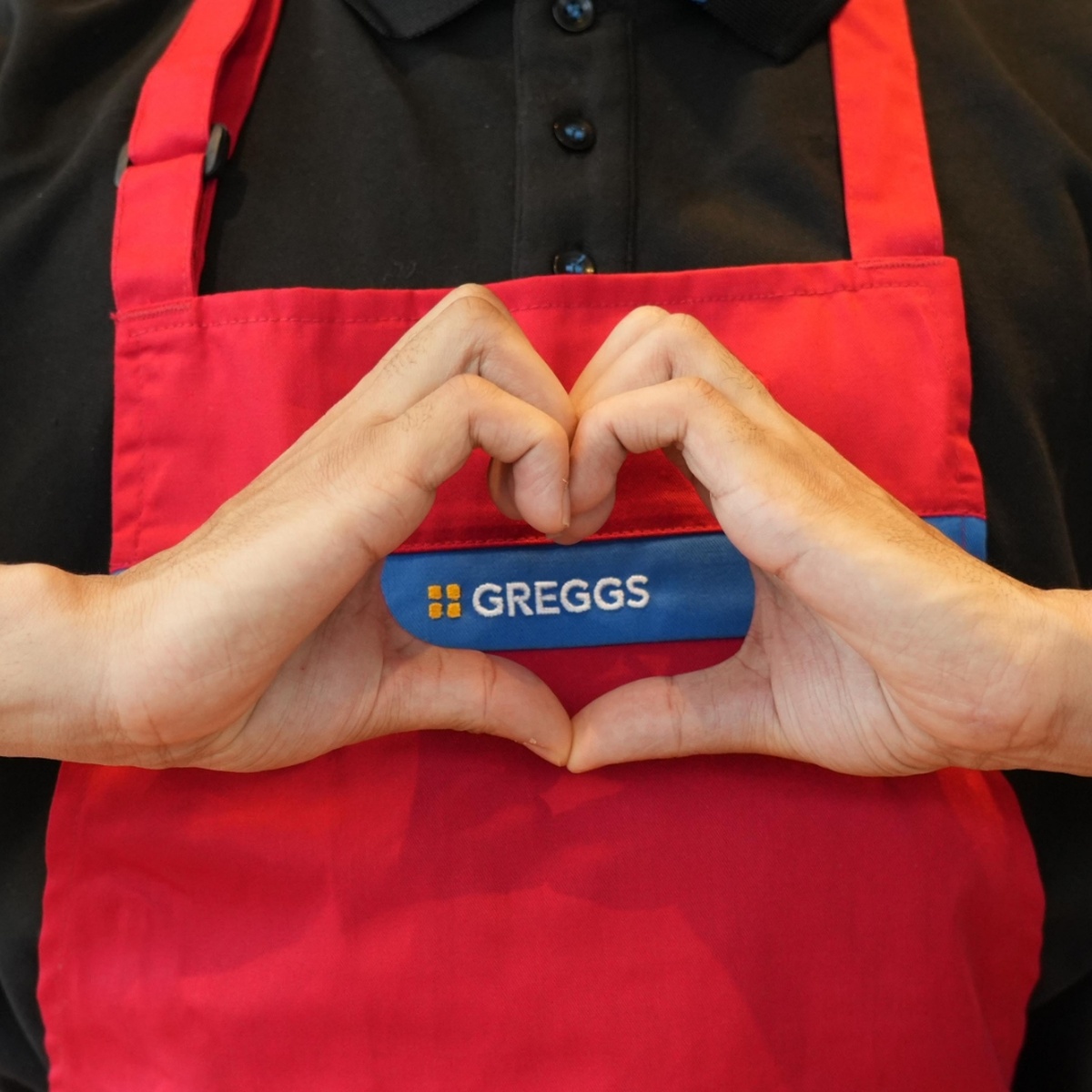 Greggs colleague making a heart shape with their hands