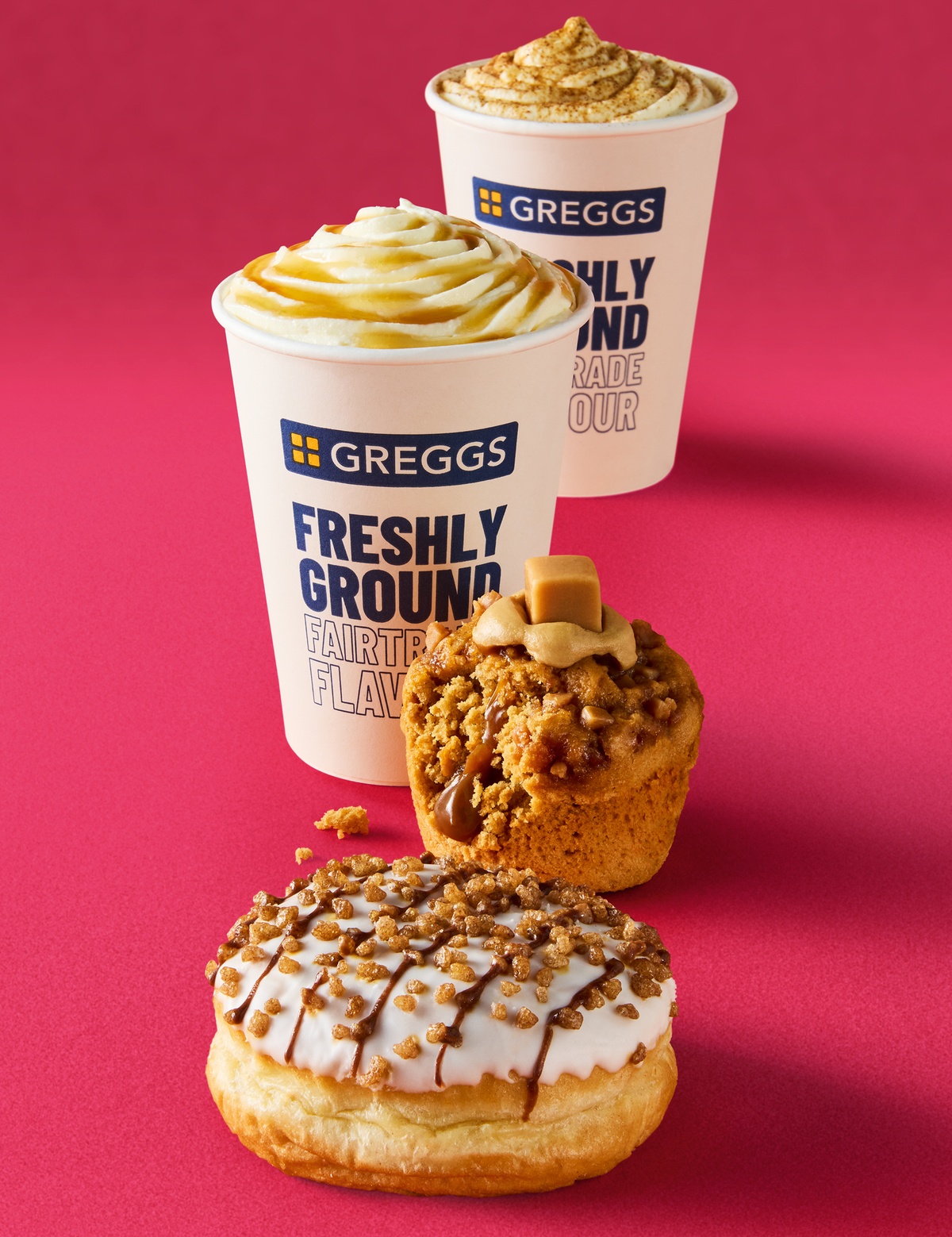 Two hot drinks with swirls of cream beside a Toffee Fudge Muffin and Pumpkin Spice Doughnut
