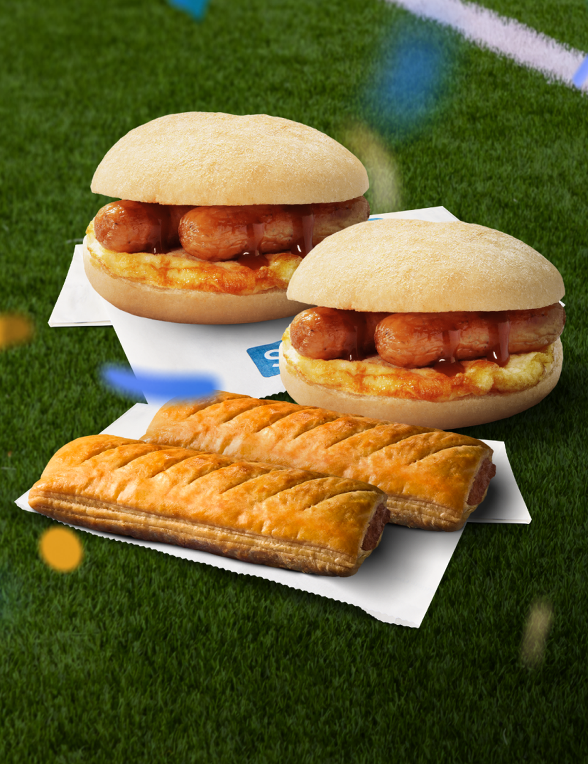 Two breakfast rolls and two sausage rolls on a football pitch, with yellow and blue confetti