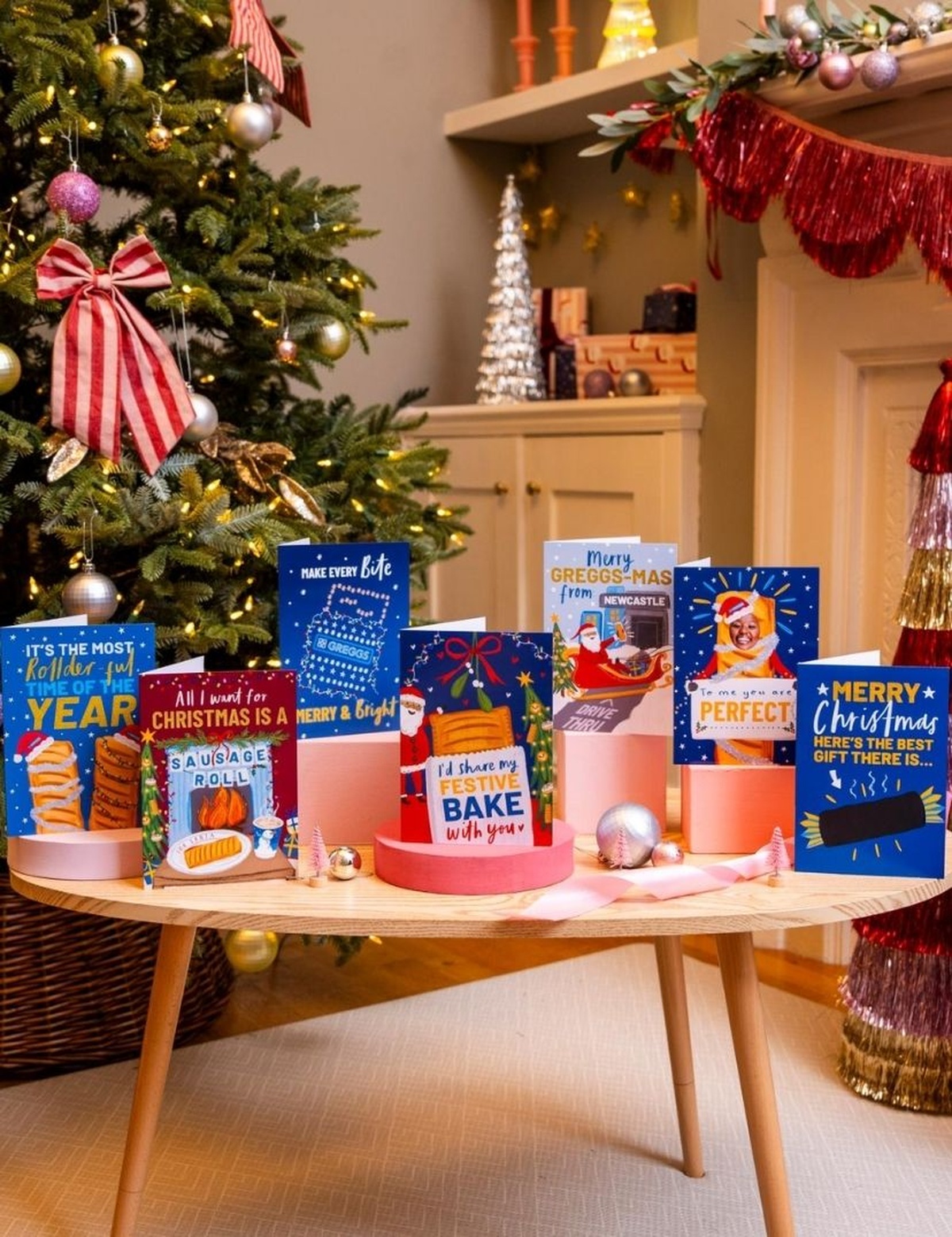 7 cards on a living room table infront of a decorated Christmas tree and fireplace mantle