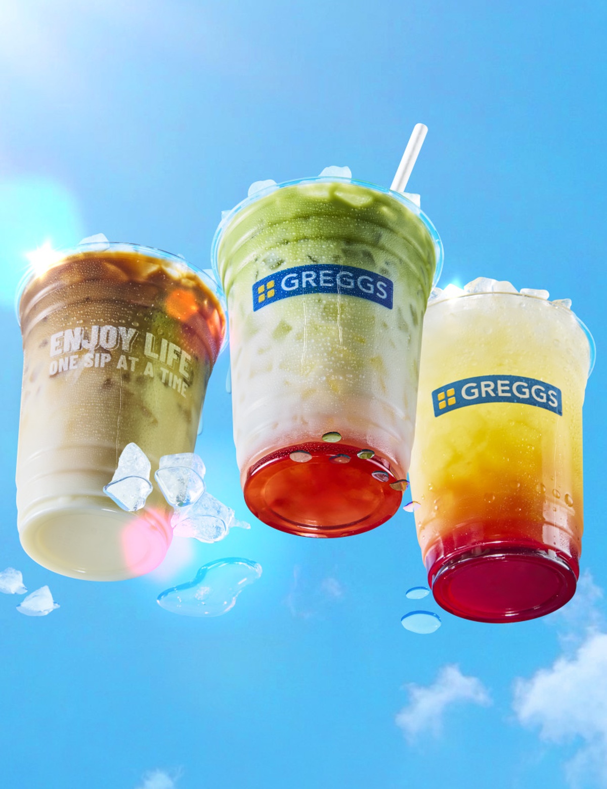 An Iced Latte, Iced Matcha Latte and Mango & Strawberry Cooler below a vibrant blue sky with condensation on the lens