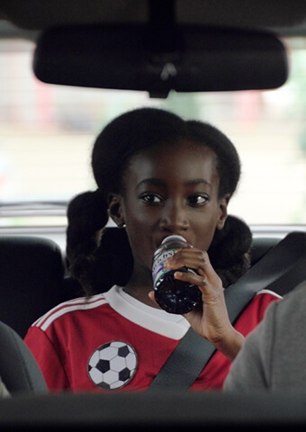 Daughter sitting in the backseat drinking Welch's grape juice on the way to soccer practice.