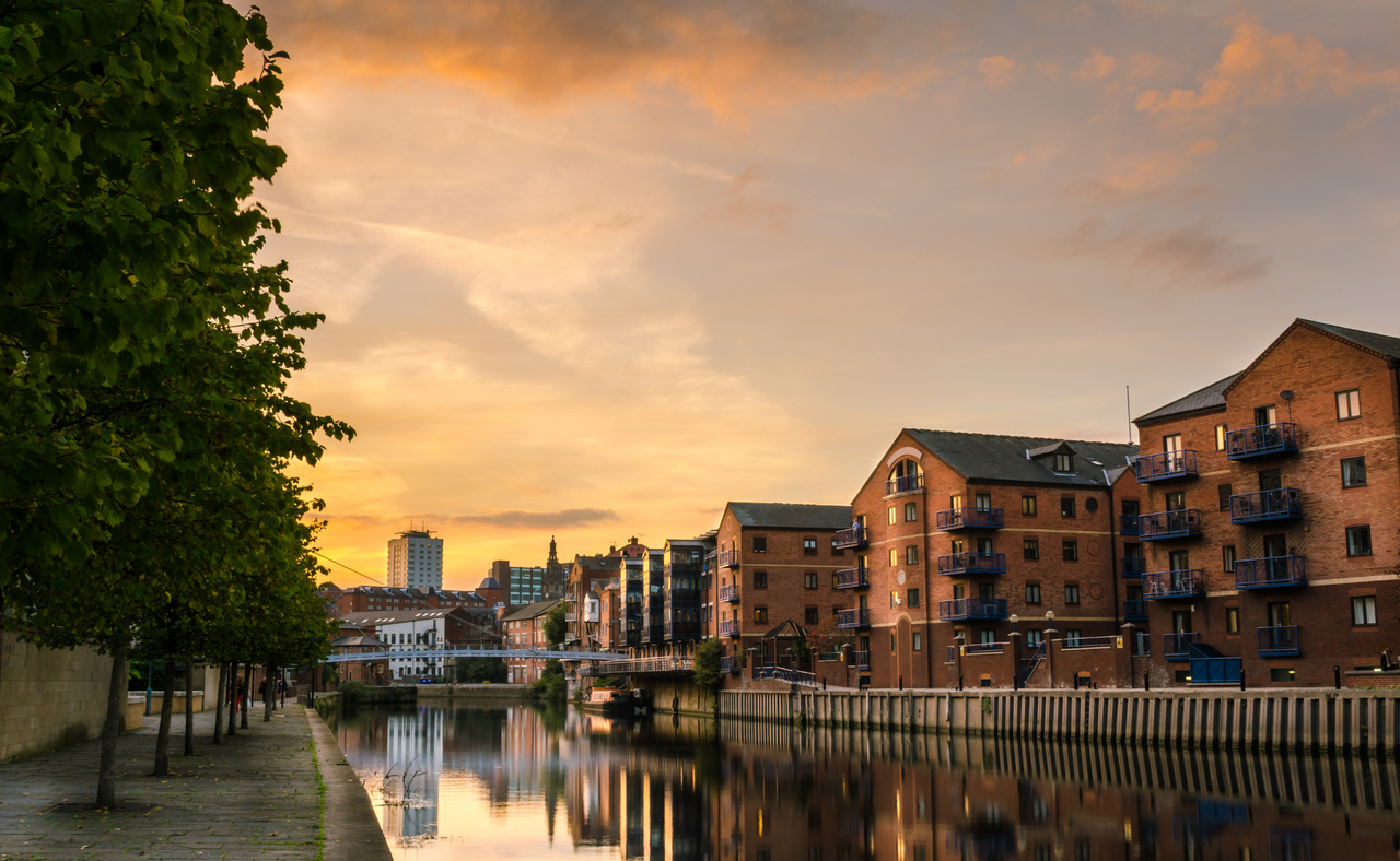 Redeveloped warehouses and modern bridge on the River Aire in Leeds at sunset