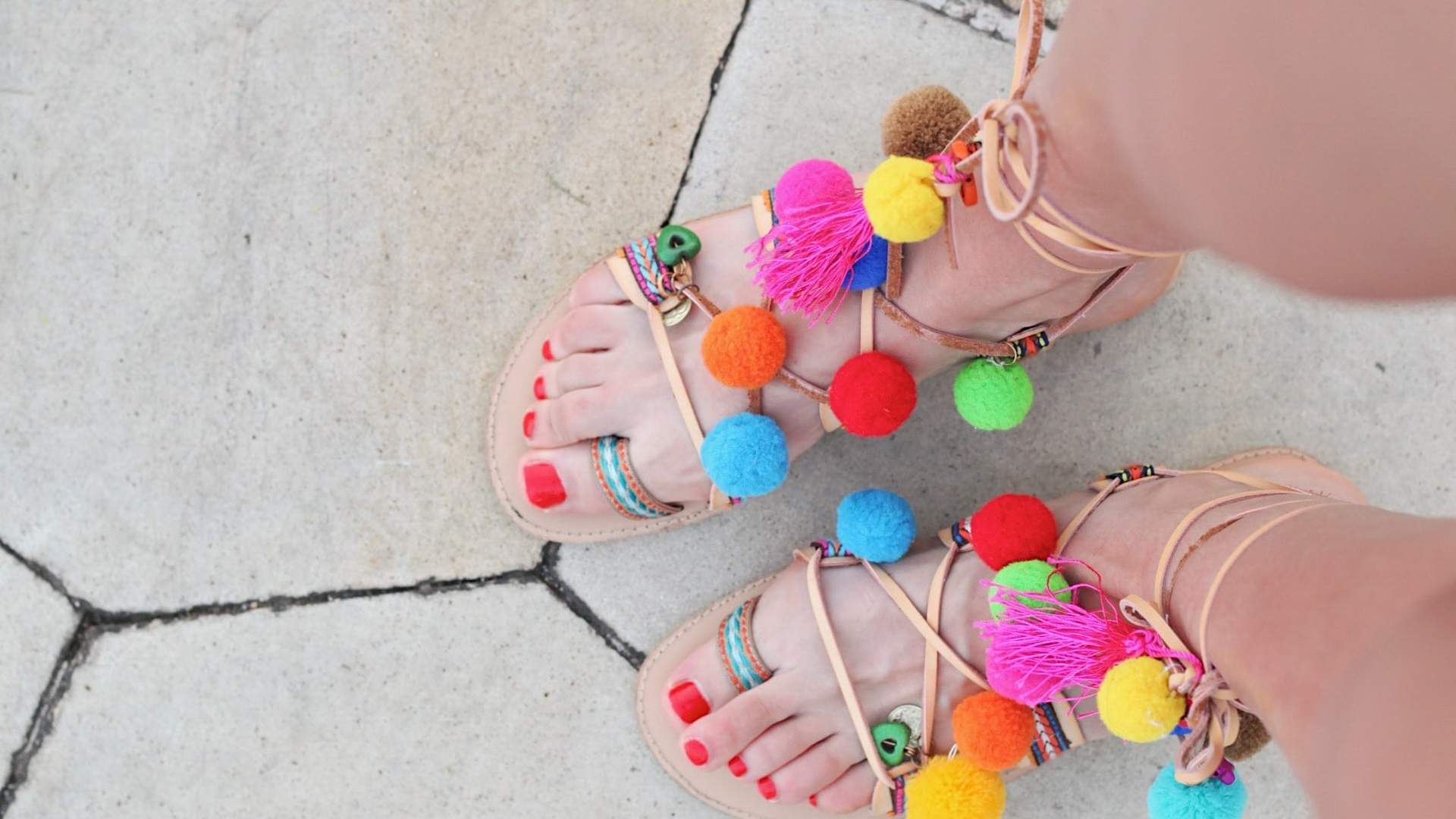 Woman with red nail polish on her feet wearing colorful sandels