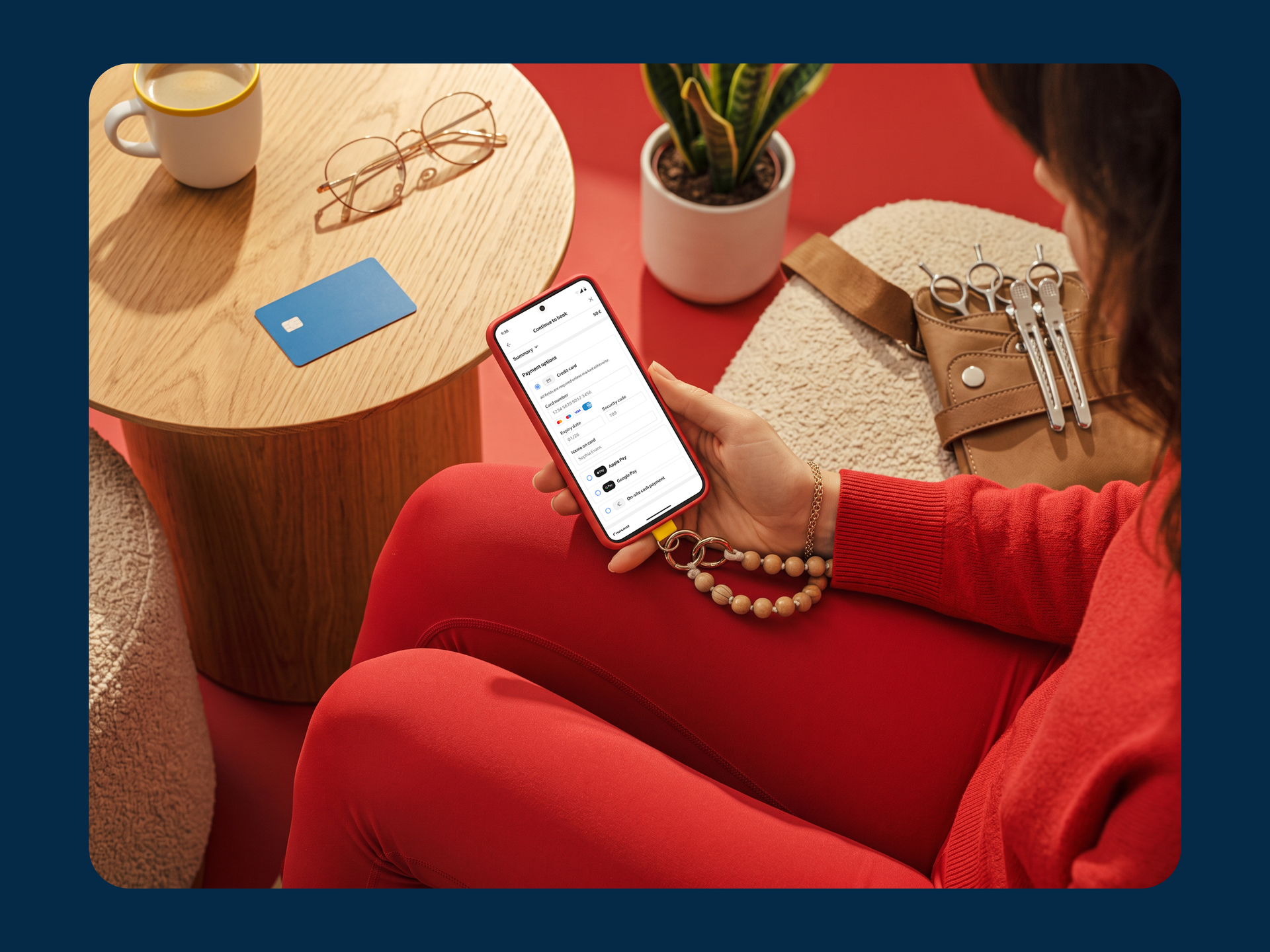 A client choosing how to pay for a salon appointment on their phone, card and glasses on the table