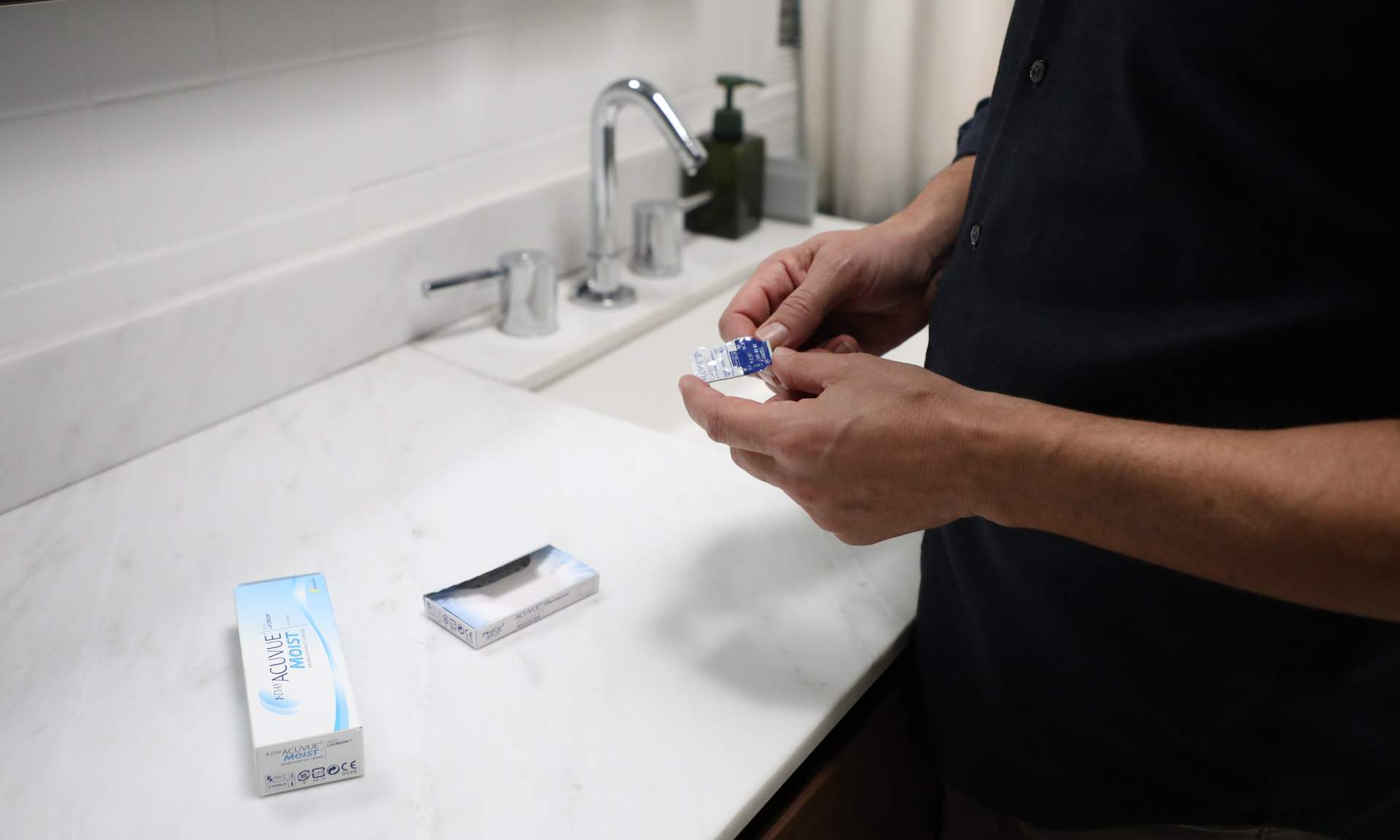 Man putting in contact lenses in the bathroom