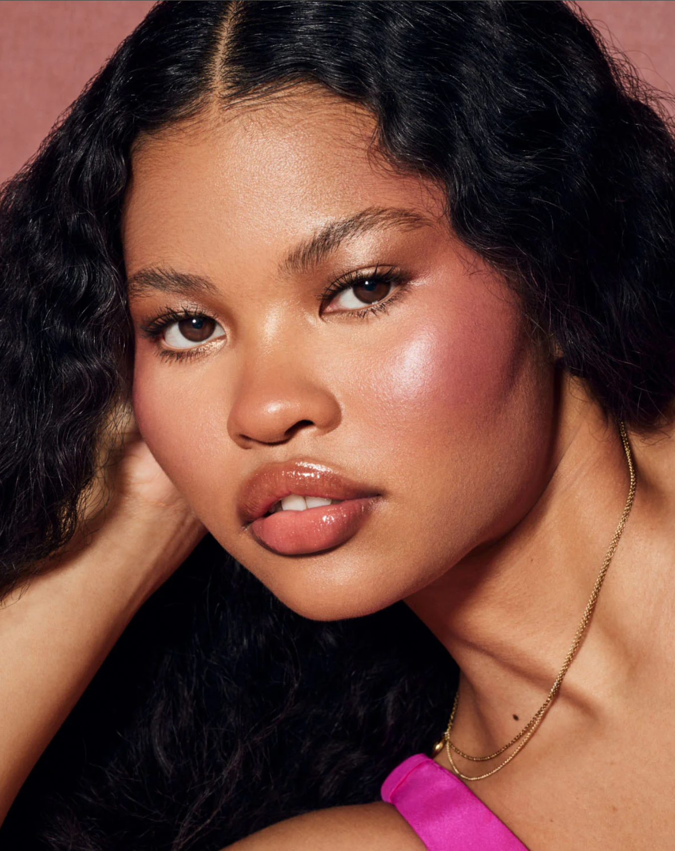 Model wearing Fenty Beauty Cheeks Suede Powder Blush in RIRI, showcasing a soft, radiant blush look