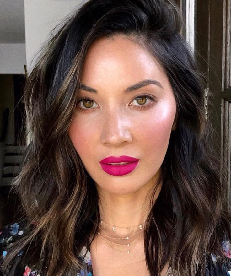 Beauty look on Olivia Munn featuring vibrant fuchsia lips and flushed pink-coral cheeks