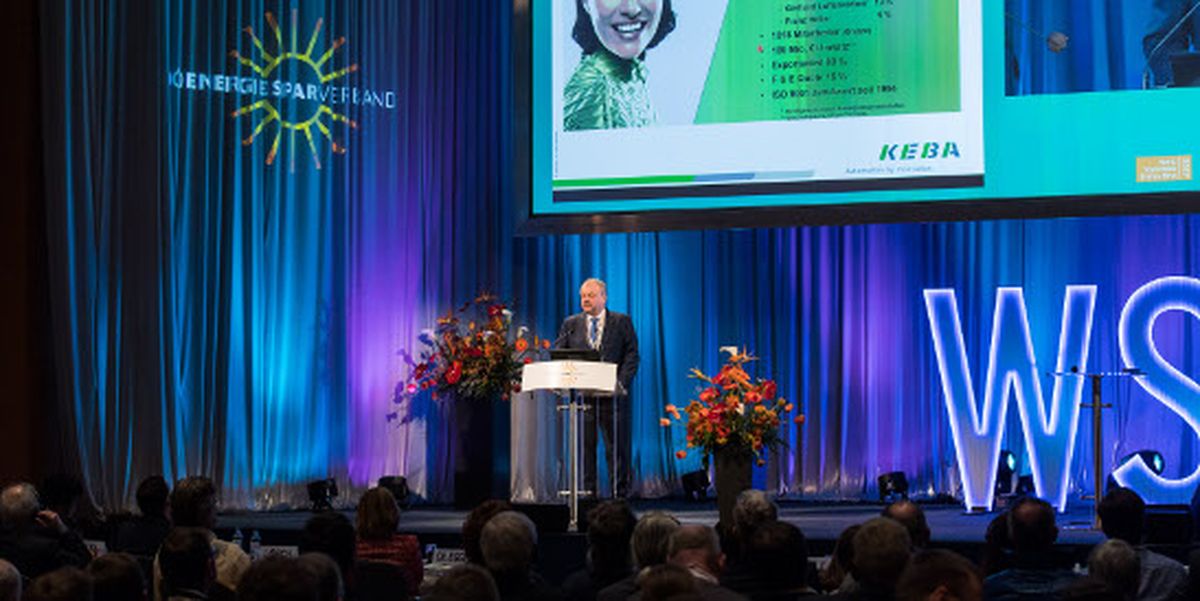 Présentation à la conférence WSED : Un intervenant prend la parole sur scène devant le public, avec des diapositives KEBA projetées en arrière-plan lors de l’événement de l’association pour les économies d’énergie.