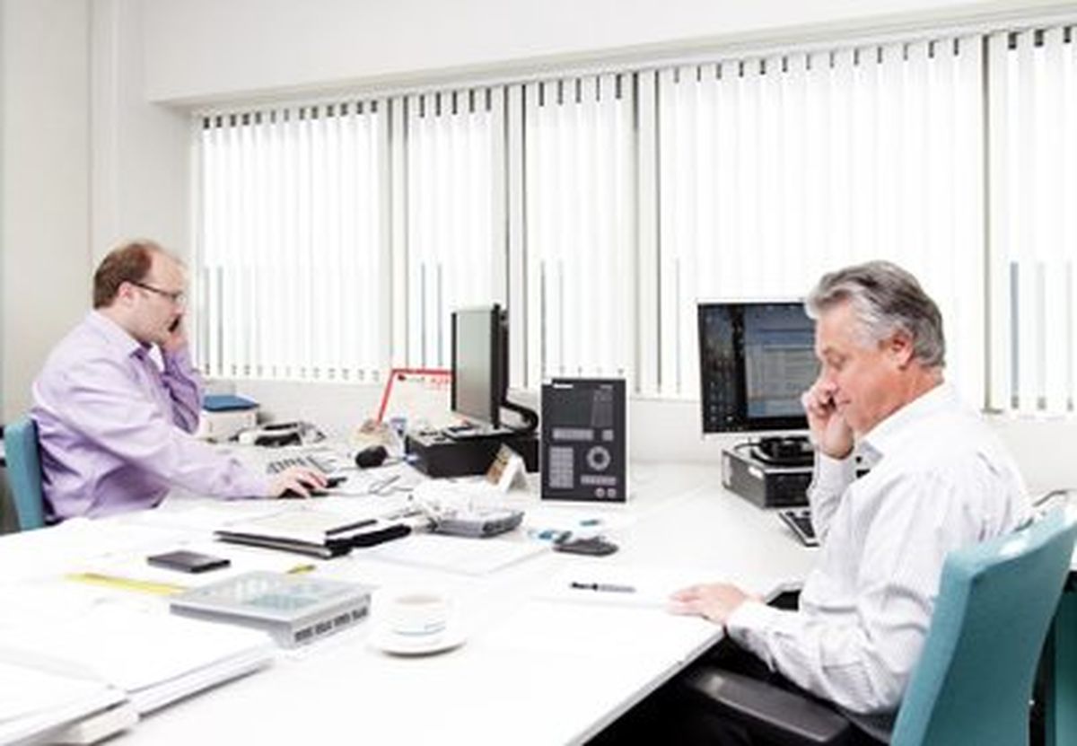 Two men in an office talking to customers on the phone